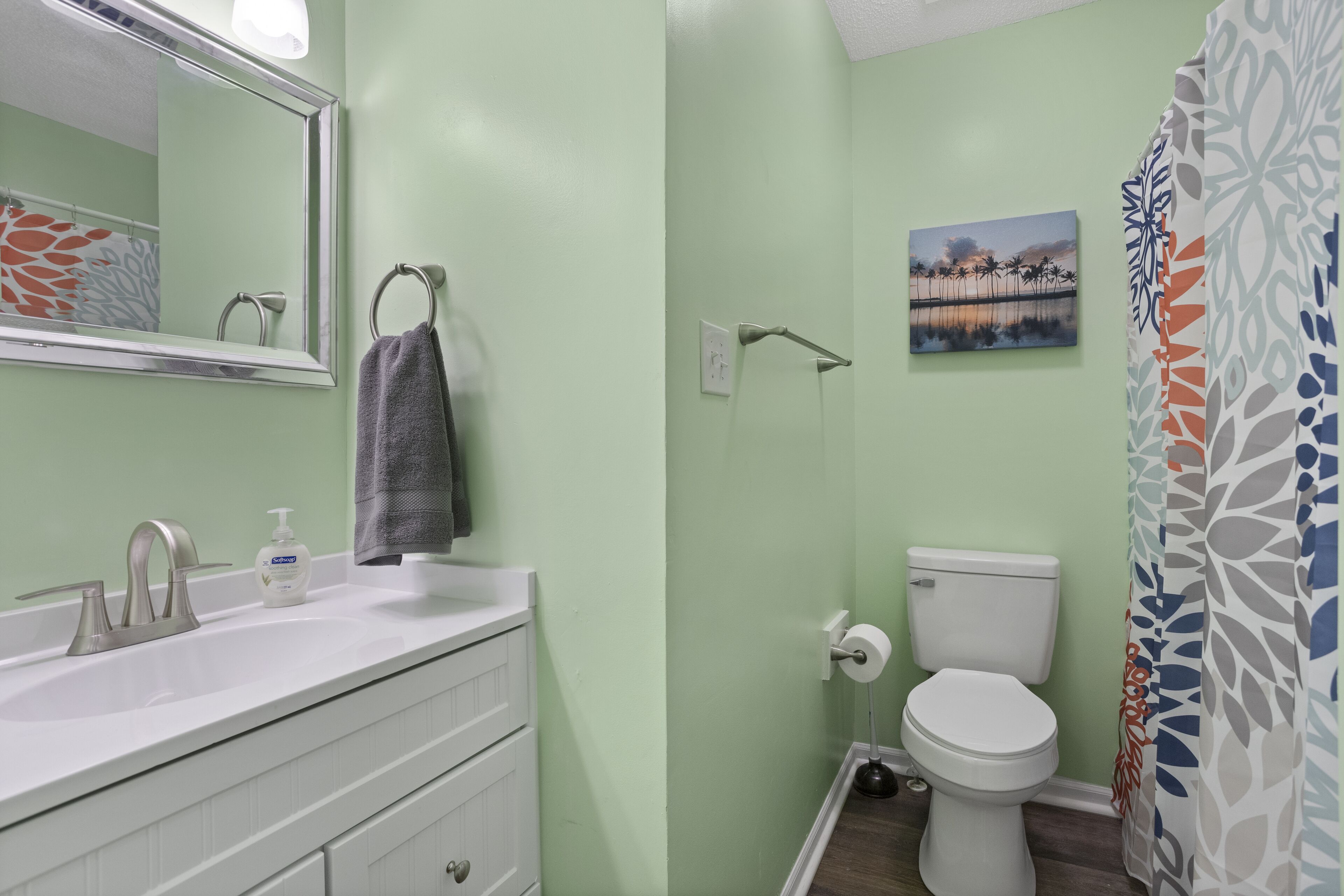 Une salle de bain avec un lavabo blanc, des toilettes et un rideau de douche.