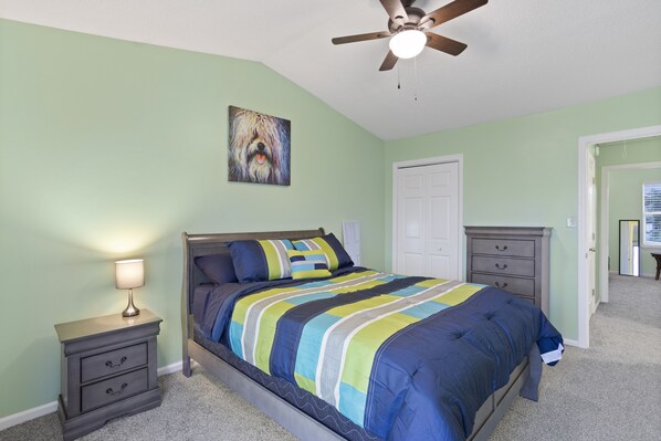 A bedroom with a bed, nightstands, a ceiling fan, and a door.