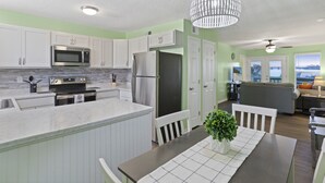 A modern kitchen with white cabinets, stainless steel appliances, and a dining area with a table and chairs. - Adorable Townhome with Water Views (Jacksonville)