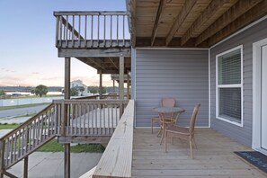 A wooden deck with a railing, a table with chairs, and a welcome mat. - Adorable Townhome with Water Views (Jacksonville)