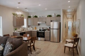 A modern kitchen with a central island, stainless steel appliances, and a dining area with a sofa and chairs. - Downtown Duplex-San Antonio Unit #1 (San Antonio)