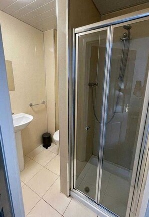 Une salle de bain avec une douche à parois de verre, un lavabo et des toilettes.