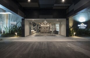 A modern hotel entrance with a glass facade, outdoor seating area, and a sign for 'MICROTEL' by Wyndham.