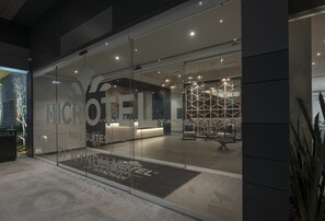 A modern hotel entrance with glass doors, a reception desk, and a patterned interior design. - Microtel Inn & Suites by Wyndham Guadalajara Sur (Tlajomulco de Zúñiga)