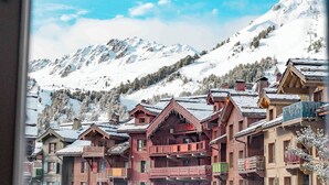 A view of a mountain village with wooden buildings and snow-covered mountains in the background.