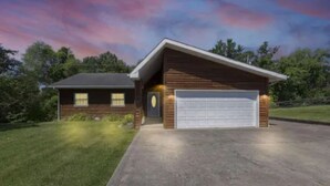 Ein zweistöckiges Haus mit Garage, Rasen und Auffahrt.