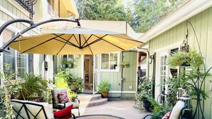 Un espace patio comprenant un coin salon abrité, un jacuzzi et diverses plantes en pot.