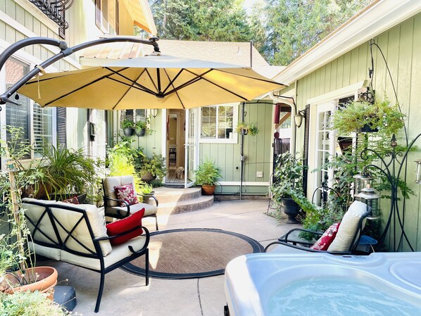 A patio area with a covered seating area, a hot tub, and various potted plants.