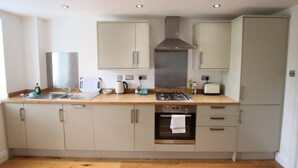 A modern kitchen with a stainless steel range hood, a built-in oven, and a wooden countertop. - Charming Flat With Private Patio in Clifton (Bristol)