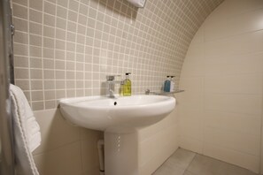A bathroom with a white sink, a towel hanging on the wall, and a tiled floor. - Charming Flat With Private Patio in Clifton (Bristol)