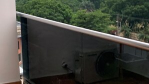 A balcony with a view of a green landscape and buildings in the distance.