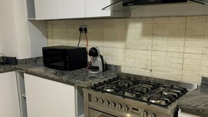 A kitchen with white cabinets, a black microwave, a gas stove, and a built-in oven.
