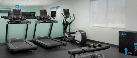 A gym with treadmills, an elliptical, and a bench press.