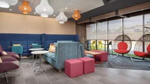 A modern lounge area with seating arrangements, including sofas and chairs, and a large window providing a view of the outdoors. - Tru by Hilton San Antonio North (San Antonio)