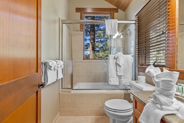 A modern bathroom with a glass-enclosed shower, a toilet, and a sink.