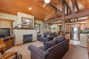 A spacious living room with a fireplace, a large sofa, and a dining area with a table and chairs. - Gull Lake Craftsman, a custom home that sleeps 10. (June Lake)