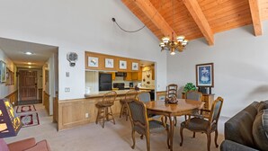 Un vaste espace de vie comprenant une table à manger en bois, quatre chaises, un canapé et une cuisine en arrière-plan.