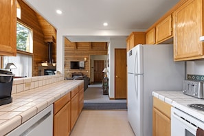 A kitchen with wooden cabinets, a white refrigerator, a stove, and a large window.