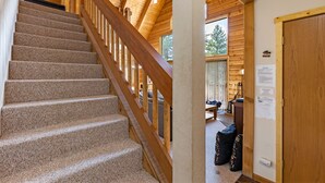 A wooden staircase with a handrail leading to a room with a ceiling fan and a view of the outdoors. - Lake View Mountain Cabin (June Lake)