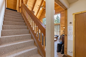 A wooden staircase with a handrail leading to a room with a ceiling fan and a view of the outdoors.
