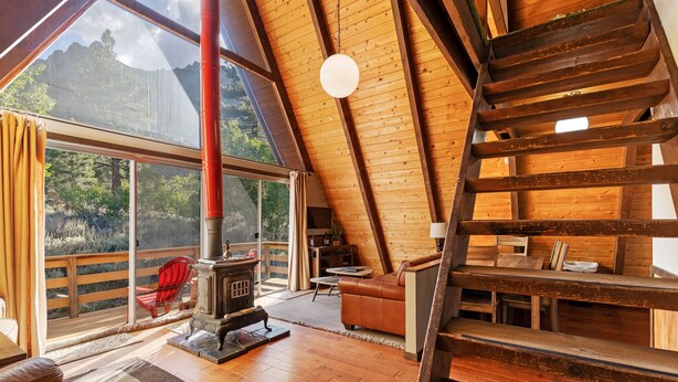 A wooden interior with a fireplace, a sofa, and a staircase. - Four Seasons Cabin 2 (June Lake)