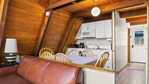 A cozy wooden cabin with a dining area, a kitchenette, and a living space with a leather sofa. - Four Seasons Cabin 5 (June Lake)