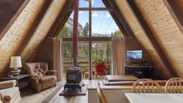 A cozy attic room with a fireplace, leather sofa, and a television. - Four Seasons Cabin 5 (June Lake)