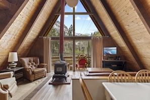 Acogedor dormitorio en el ático con chimenea, sofá de cuero y televisor.