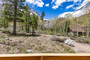 A mountainous landscape with a house surrounded by trees and a dirt path.