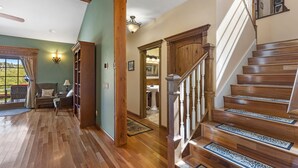 Une pièce spacieuse dotée de planchers en bois, d’un escalier avec une rampe en bois et offrant une vue sur l’extérieur grâce à une grande fenêtre.