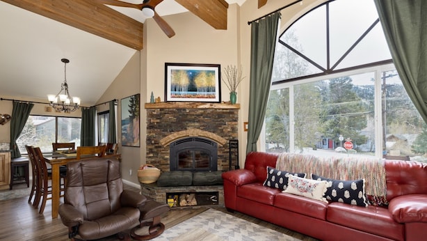 A living room with a fireplace, leather sofa, dining area, and large windows. - Edgewater 19, steps from the June Lake Marina. (June Lake)