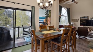 A dining area with a wooden table and chairs, a chandelier, and a painting of a landscape. - Edgewater 19, steps from the June Lake Marina. (June Lake)