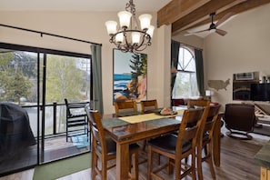 A dining area with a wooden table and chairs, a chandelier, and a painting of a landscape.