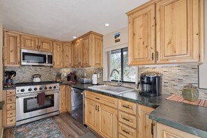 A kitchen with wooden cabinets, a stainless steel oven, a microwave, and a coffee maker.