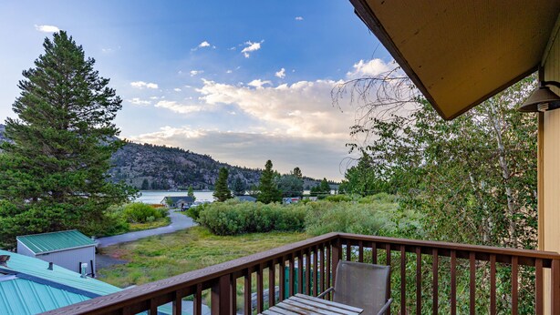 Une terrasse en bois offrant une vue sur un lac et des collines.