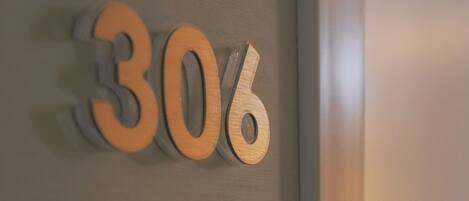 Un letrero en la pared con los números '30' y '6' en una tipografía moderna, probablemente indicando un número de habitación o sección.