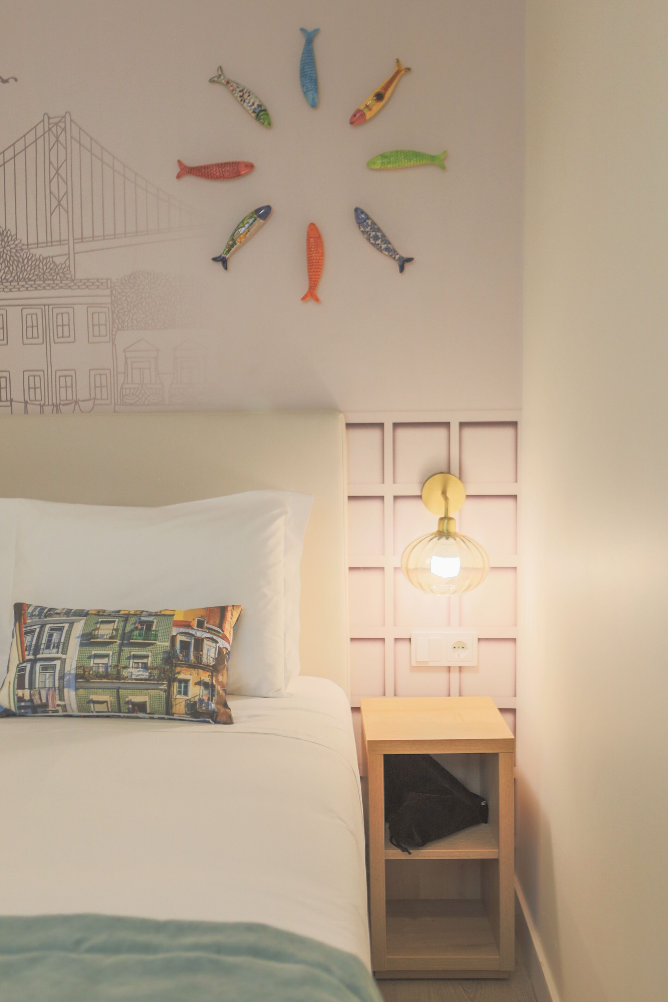 Un dormitorio con cama, mesita de noche, lámpara de pared y decoración de peces y un puente.