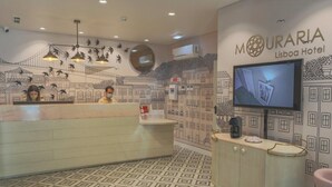 A reception area with a patterned floor, a counter with a coffee machine, and a TV mounted on the wall. - Mouraria Lisboa Hotel (Lisbon)