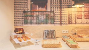 A kitchen with a toaster, a basket of bread, and a display of pastries. - Mouraria Lisboa Hotel (Lisbon)