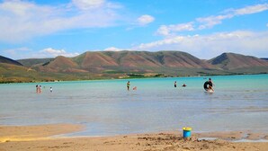 A beach with clear turquoise water, people swimming and playing, and mountains in the background. - Red Barn Retreat in the Heart of Bloomington  (Bloomington)