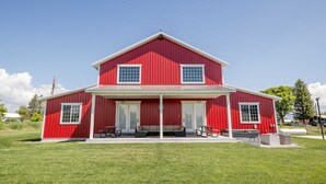 A red two-story house with a covered porch, large windows, and a well-maintained lawn. - Red Barn Retreat in the Heart of Bloomington  (Bloomington)