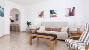 A modern living room with a sofa, a striped armchair, a wooden coffee table, and abstract art on the wall. - Home2book Sea Front El Granillo, Beach & Wifi (Costa Calma)