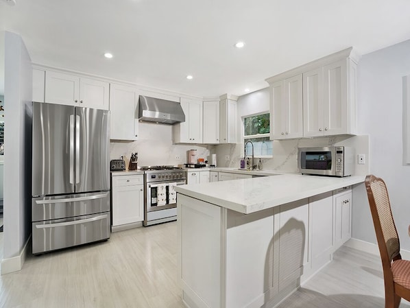 A modern kitchen with white cabinetry, stainless steel appliances, and a central island.