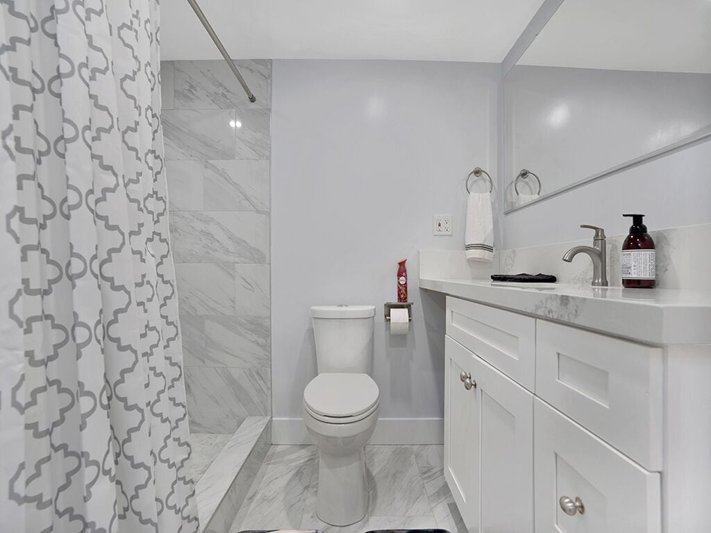 Une salle de bain moderne équipée de toilettes, d’un lavabo et d’un rideau de douche.