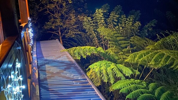 Ein hölzerner Weg mit Lichterketten führt zu einem Gebäude.