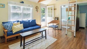 Una sala de estar acogedora con un sofá azul, un banco de madera y una escalera que lleva a una zona superior.