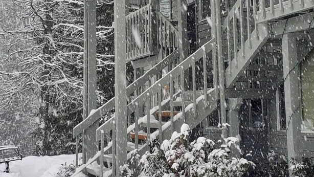 A building with a covered porch and multiple staircases leading to the entrance. - Schweitzer Mountain Condo (Sandpoint)