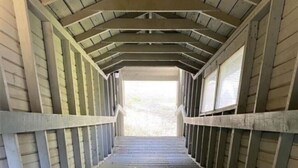A covered wooden walkway with a sloped roof and metal railings. - Schweitzer Mountain Condo (Sandpoint)