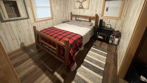 A cozy bedroom with a wooden bed, a fireplace, and a deer wall art.