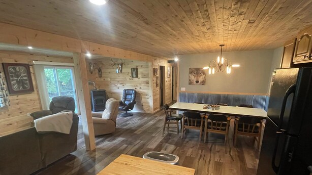 A cozy cabin interior with a dining area, a fireplace, and a kitchen.